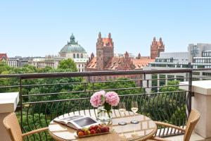 a table with flowers on a balcony with a view of the city at Rocco Forte The Charles Hotel in Munich