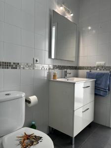een badkamer met een toilet, een wastafel en een spiegel bij CONIL CENTRO MERCURIO solo FAMILIAS in Conil de la Frontera +20 foto's