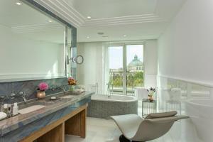 a bathroom with a tub and a sink and a bath tub at Rocco Forte The Charles Hotel in Munich