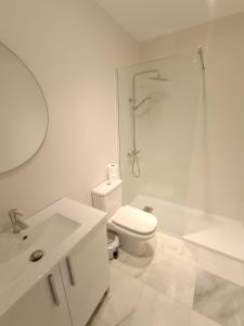 a white bathroom with a toilet and a shower at Ribera del río - Centro in El Puerto de Santa María +8 photos