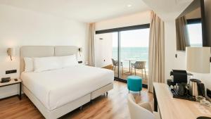 a hotel room with a bed and a desk and a room with a view at Sercotel Cruz Del Mar in Chipiona