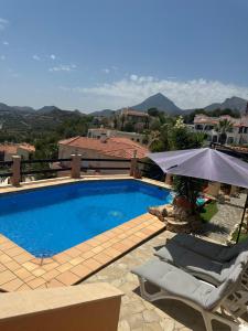 a swimming pool with two chairs and an umbrella at Cozy vacation home in L’Alfàs del Pi