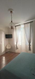 a bedroom with a bed and a chandelier and windows at Esperia Maison B&b in Montesarchio +9 photos