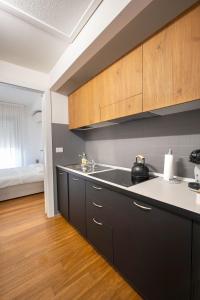 a kitchen with black cabinets and a sink and a bed at L'Alicanto - Bilocale zona centro in Pordenone +11 photos