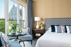 a bedroom with a bed and a chair and a window at Rocco Forte The Charles Hotel in Munich