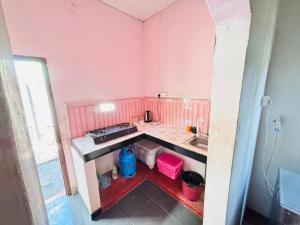 Una pequeña cocina rosa con fregadero y estufa. en Spl inn, en Trincomalee 16 fotos más