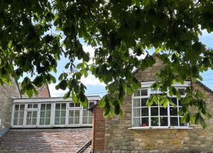 a brick house with white windows and a tree at Apartment above Samantha Dadd Art Studio - in the Cotswolds in Tewkesbury