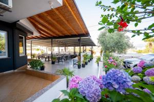 Un patio con mesas y sillas y flores moradas. en Sunshine Hotel, en Ksamil