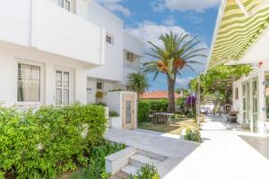 a white house with a garden and palm trees at Mon Ilıca Otel in Çeşme