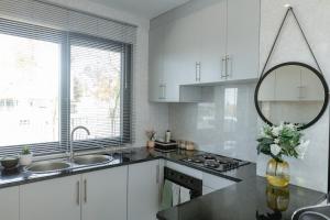 a kitchen with white cabinets and a sink and a mirror at The AntBox Kingsland City Ibexhill in Lusaka +5 photos