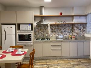 a kitchen with a table and a white refrigerator at Apê coração BC 1 qto 4 pess 300m Praia Garagem Priv in Balneário Camboriú