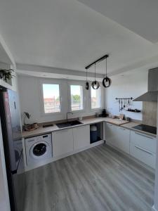 una gran cocina blanca con armarios blancos y ventanas en Appartement la gare, en Tarbes