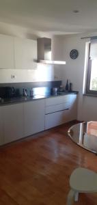 a kitchen with white cabinets and a wooden floor at Casa Pratolungo in Velletri