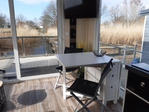 una scrivania bianca e una sedia in una stanza con finestra di Hausboot-schwimmendes-Ferienhaus-im-Havelbogen-Haus-auf-dem-Wasser a Kützkow