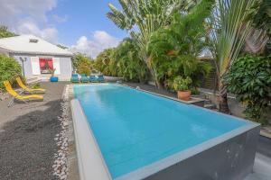 サン・フランソワにあるVilla 5 étoiles Piscine à débordement accès PMRのヤシの木が茂る庭にある青い大型スイミングプール