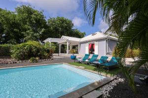 サン・フランソワにあるVilla 5 étoiles Piscine à débordement accès PMRの青い椅子付きのスイミングプール、家