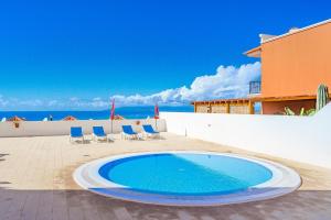 einen Pool auf einer Terrasse mit Stühlen und Meerblick in der Unterkunft Tantulia bungalow El Conde 2 rooms in Adeje