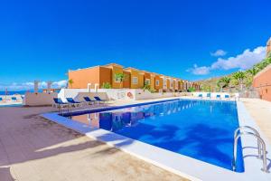 ein großer Pool mit Stühlen neben einem Gebäude in der Unterkunft Tantulia bungalow El Conde 2 rooms in Adeje
