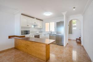 eine Küche mit weißen Schränken und einer Holzarbeitsplatte in der Unterkunft Tantulia bungalow El Conde 2 rooms in Adeje