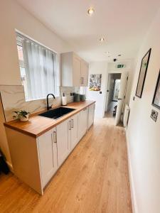 a kitchen with white cabinets and a wooden floor at R4 - Luxury fully Self-Contained Studio with Private Bathroom and Kitchen in Halesowen