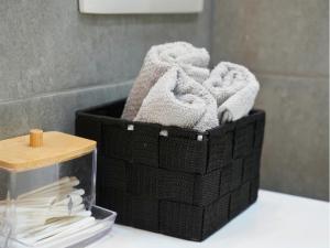 a black basket filled with towels on a bathroom counter at Duplex familiale 3 chambres, 3 salles de bains & jardin à Bruxelles by CYGO Gestion in Brussels +29 photos