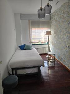 a bedroom with a bed and a chair and a window at Winahost Salvora en Primera Línea de Mar in Ribeira