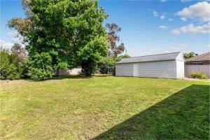 a large yard with a garage and a tree at Bendigo Bliss - Cheerful & Spacious Home in Bendigo in Kangaroo Flat