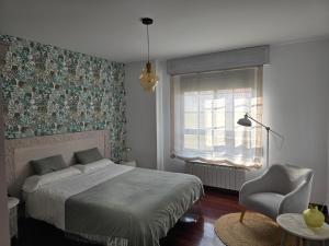 a bedroom with a bed and a chair and a window at Winahost Salvora en Primera Línea de Mar in Ribeira +7 photos