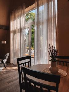 a dining room with a table and a large window at Mulberynas in Stakliškės