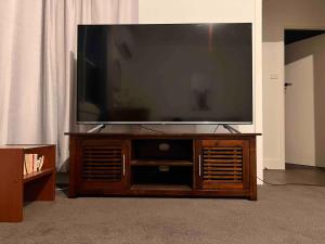 a large flat screen tv on a wooden entertainment center at Bendigo Bliss - Cheerful & Spacious Home in Bendigo in Kangaroo Flat +12 photos