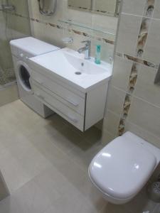La salle de bains est pourvue d'un lavabo blanc et de toilettes. dans l'établissement Apartment Lenina 9/11, à Oufa