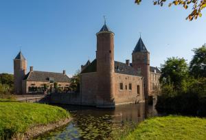 an old castle with two towers on a river at Sfeervol chalet op familiepark in Oostkapelle vlakbij strand in Oostkapelle