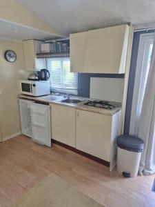 eine kleine Küche mit weißen Schränken und einer Spüle in der Unterkunft Mobil-home 4 personnes in Bec-de-Mortagne