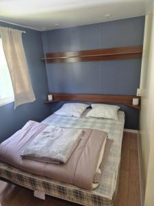 Bett in einem Schlafzimmer mit blauer Wand in der Unterkunft Mobil-home 4 personnes in Bec-de-Mortagne
