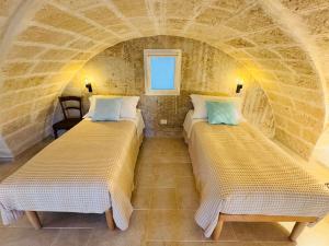 two beds in a room with a stone wall at Annina guest house soggiorno vista mare in Savelletri di Fasano +26 photos