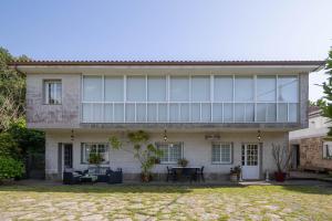 ein großes Haus mit Glasfenstern und einem Garten in der Unterkunft Casa da Carballeira in A Estrada