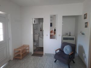 a living room with a chair and a bathroom at Apartman Meli in Rab