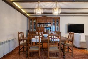 ein Esszimmer mit Tisch und Stühlen und einem Fernseher in der Unterkunft Casa da Carballeira in A Estrada