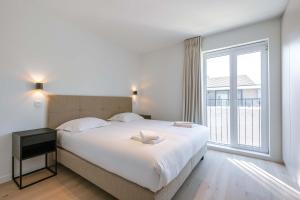 a bedroom with a large bed and a large window at Huswell - New Beach Apartment in De Haan in De Haan