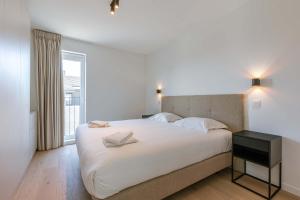 a bedroom with a large white bed and a window at Huswell - New Beach Apartment in De Haan in De Haan +30 photos