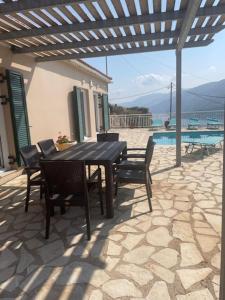 eine Terrasse mit Tisch und Stühlen und einem Pool in der Unterkunft Villa Eros in Zóla