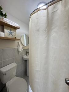 a bathroom with a white shower curtain and a toilet at The Cozy Clouds Staycation in Suba +8 photos