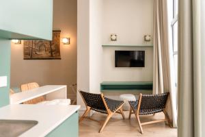 a living room with chairs and a table and a tv at Honest Sevilla Apartments in Seville