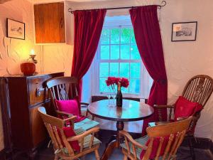 una sala da pranzo con tavolo, sedie e una finestra di The Buttoned Hearth in Ullswater a Penrith Altre 16 foto