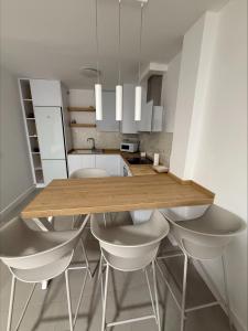 Una cocina con una mesa de madera y sillas blancas. en Luxury San Jose, en San José