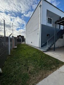 a white building with a staircase next to a yard at Amanecer Rio Limay in Plottier