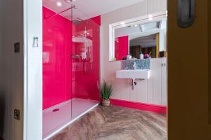 a pink bathroom with a shower and a sink at Ffolkes in Hillington