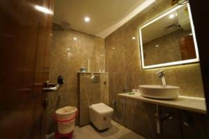 a bathroom with a sink and a toilet and a mirror at Hotel Saket In Prayagraj in Prayagraj