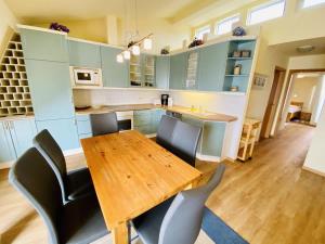 a kitchen with blue cabinets and a wooden table and chairs at Sonnendeck, direkt am Leuchtturm in Warnemünde