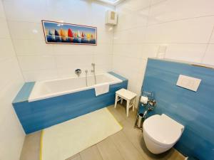 a bathroom with a blue and white tub and a toilet at Sonnendeck, direkt am Leuchtturm in Warnemünde +17 photos